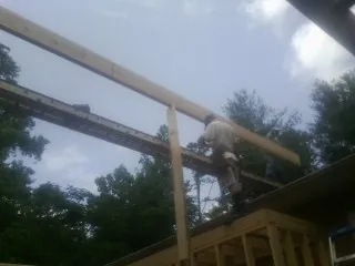 Carpenter setting a ridge beam over a new addition frame — Ice Dam Removal by Roofing Brothers in Linton