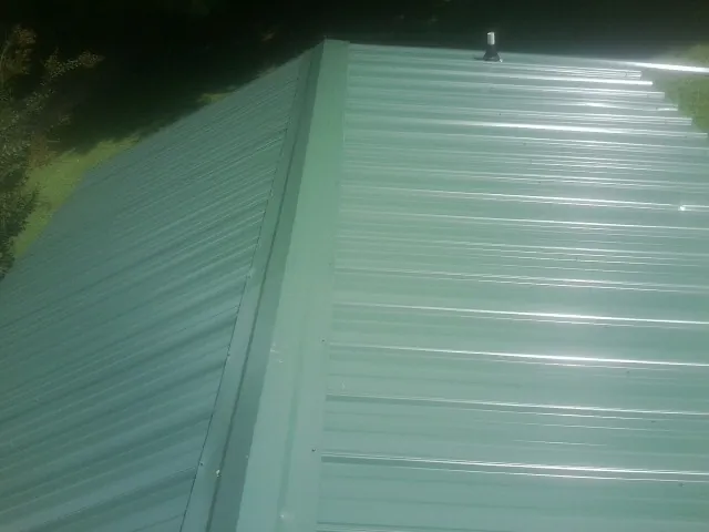 New green metal panels meeting at the ridge of a roof — Flat Roof Repair work by our crew in Linton