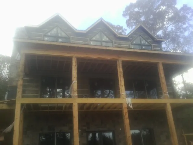 Dormers and porch framing on a large log home under construction — Roof Coating work by our crew in Linton