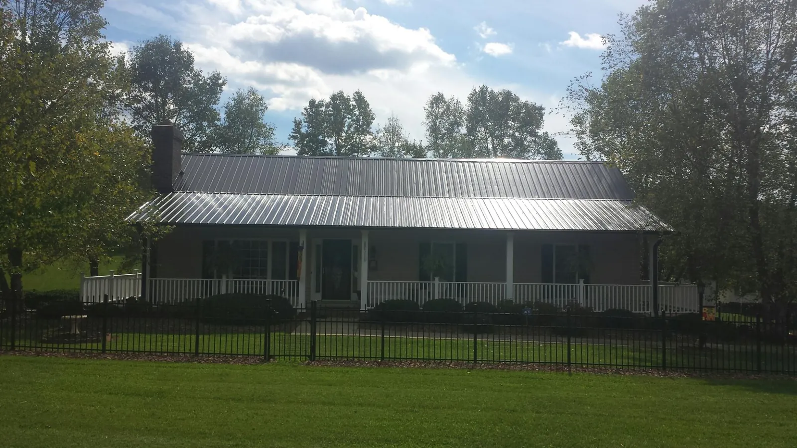 Gray metal roof on a brick ranch with a full width front porch — Gutter Guard Installation work by our crew in Linton