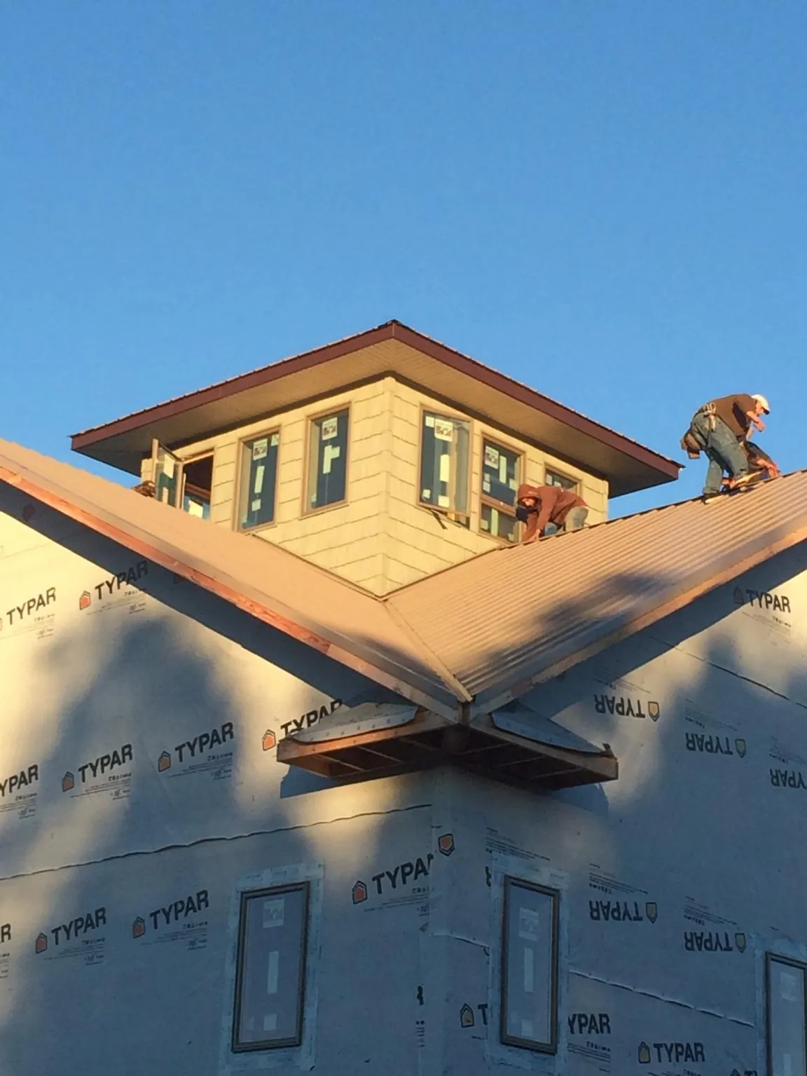 Roofers working around a rooftop cupola on a new metal roof at sunset — Roof Waterproofing in Linton by Roofing Brothers